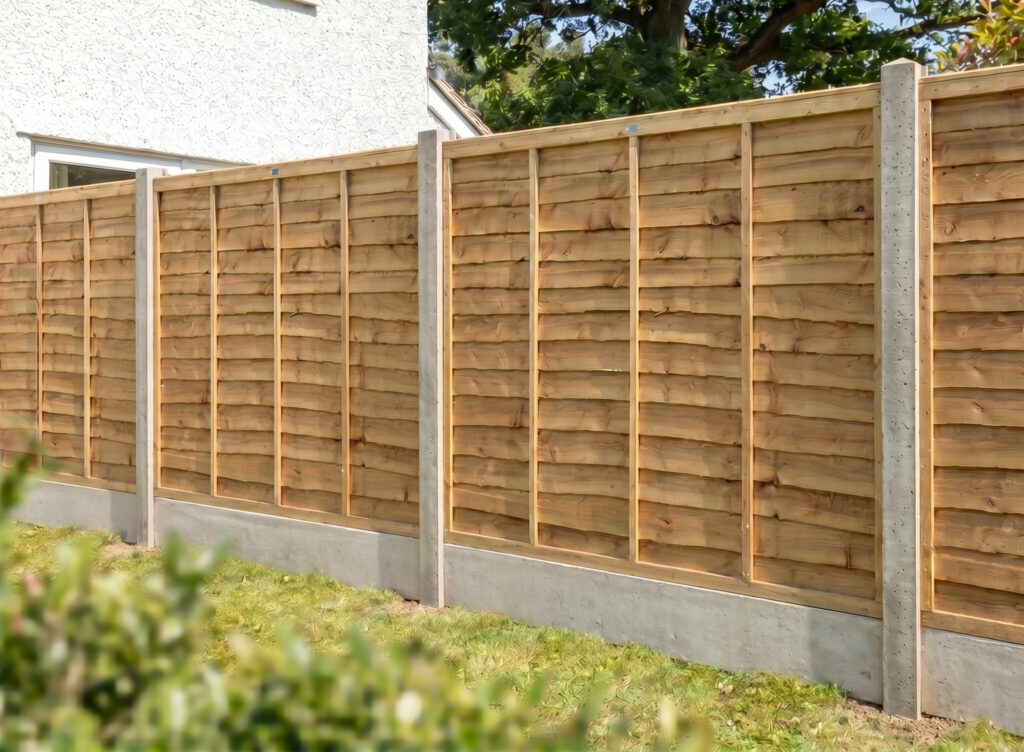 Completed lap panel fencing fitted between concrete posts above concrete gravel boards
